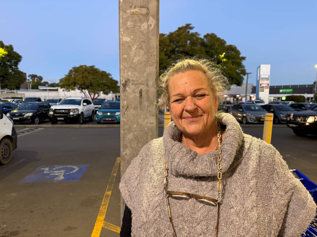 A woman wearing a grey poncho smiles.