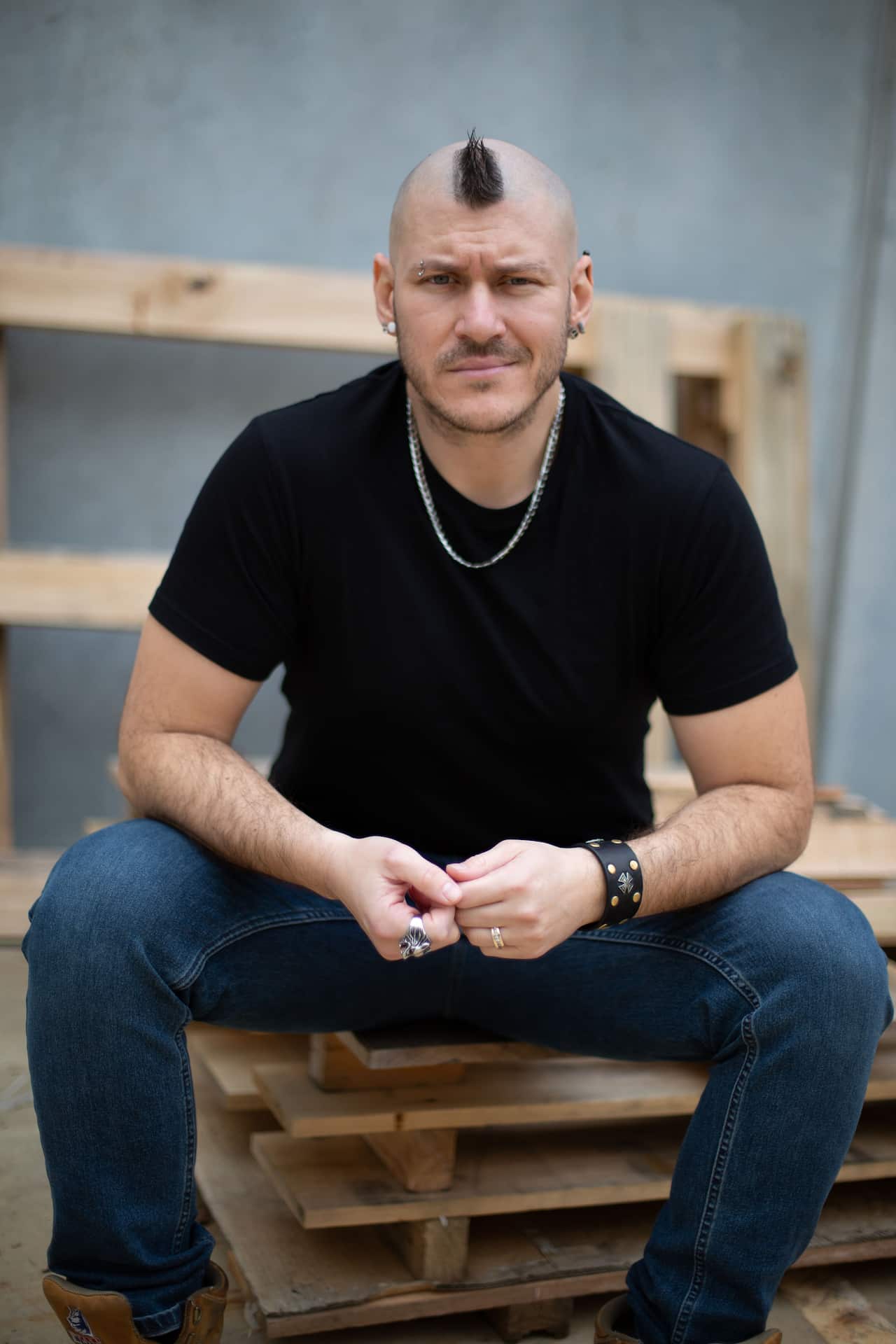 A man with s mohawk in a black t-shirt.
