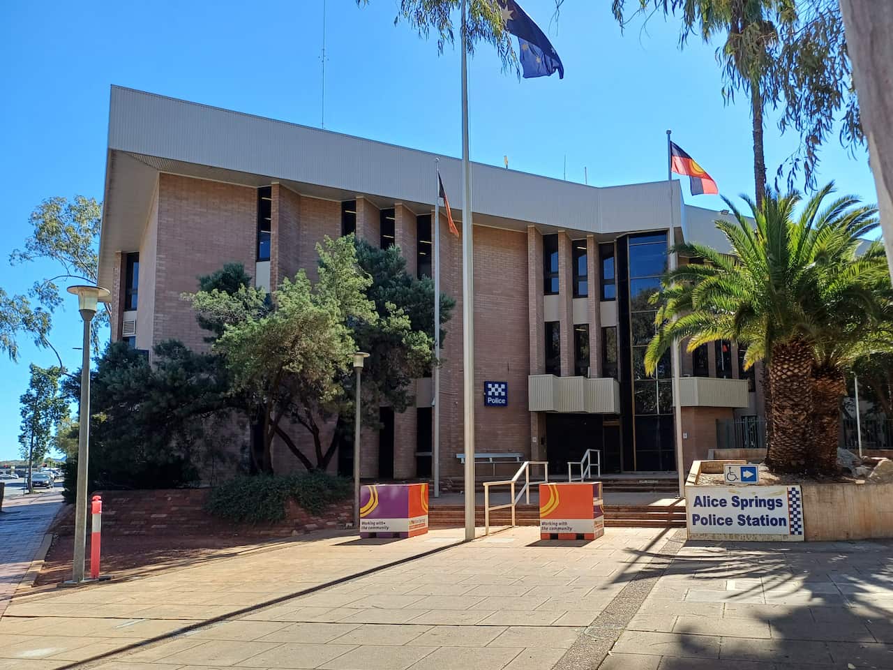 A beige brick building with a blue sky and palm trees