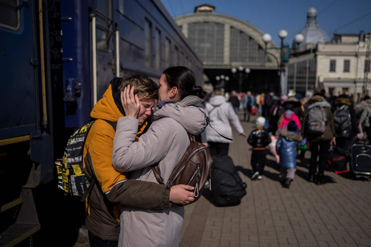 A mother is seen embracing her son at a train station.