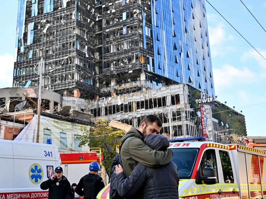 People react outside a partially destroyed multistorey office building after several Russian strikes hit the Ukrainian capital of Kyiv.