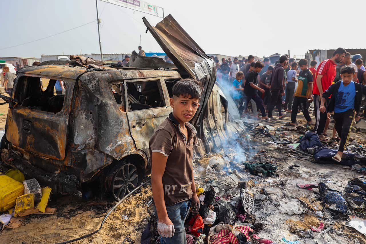 A young boy stands amid ruins after an air strike at a camp for displaced people in Rafah