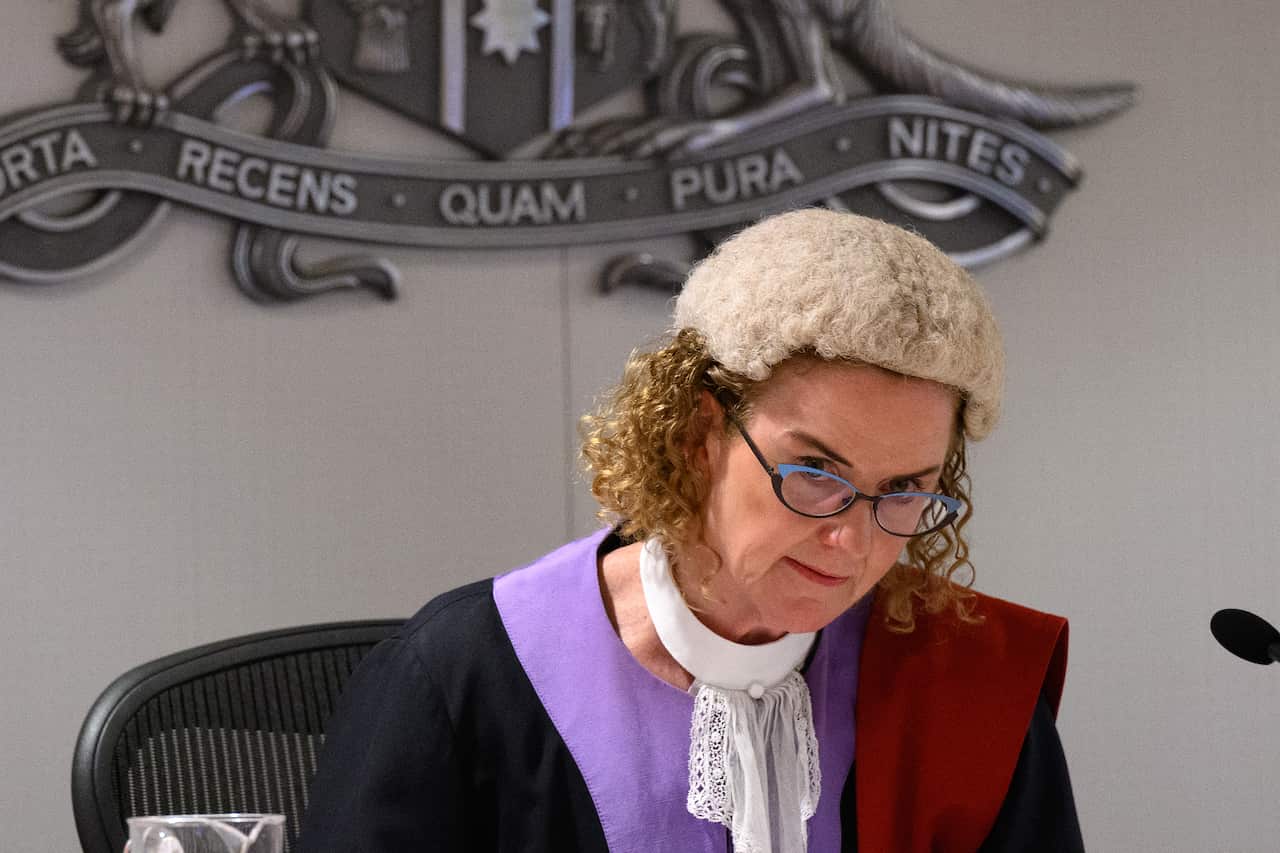 A judge with glasses delivers a verdict.