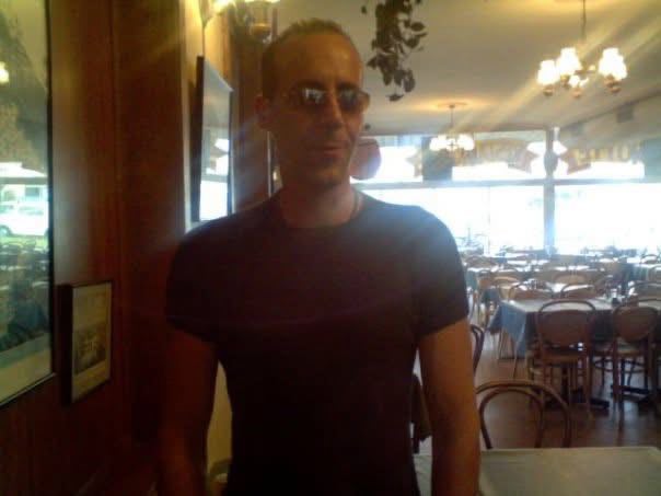 A man wearing sunglasses stands in a restaurant.