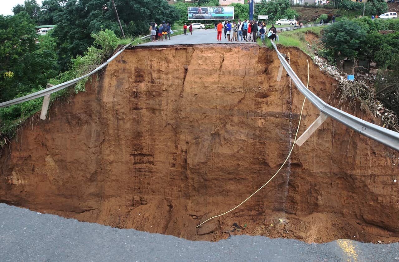 Stranded people stand in front of a bridge that was swept away in Ntuzuma, outside Durban, South Africa on 12 April 2022. 