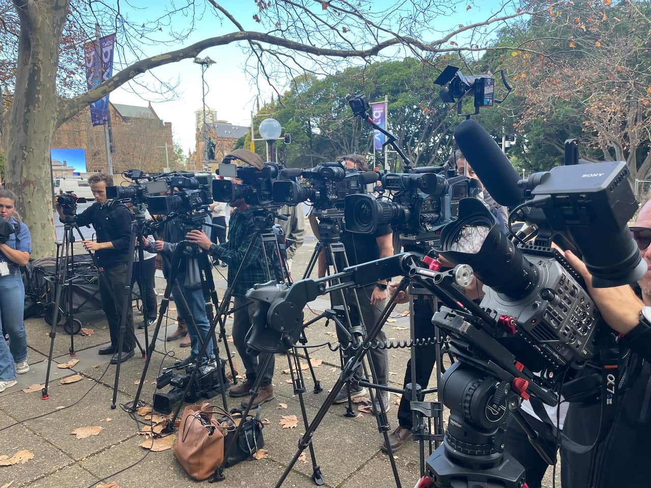 People standing behind television cameras outside
