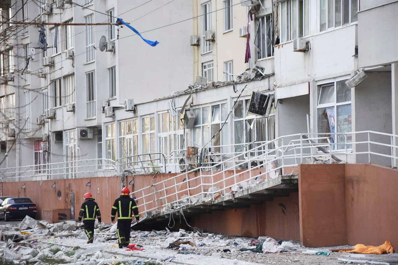 Firefighters walk past an apartment building damaged by Russian shelling in Odesa, Ukraine on 23 April 2022.