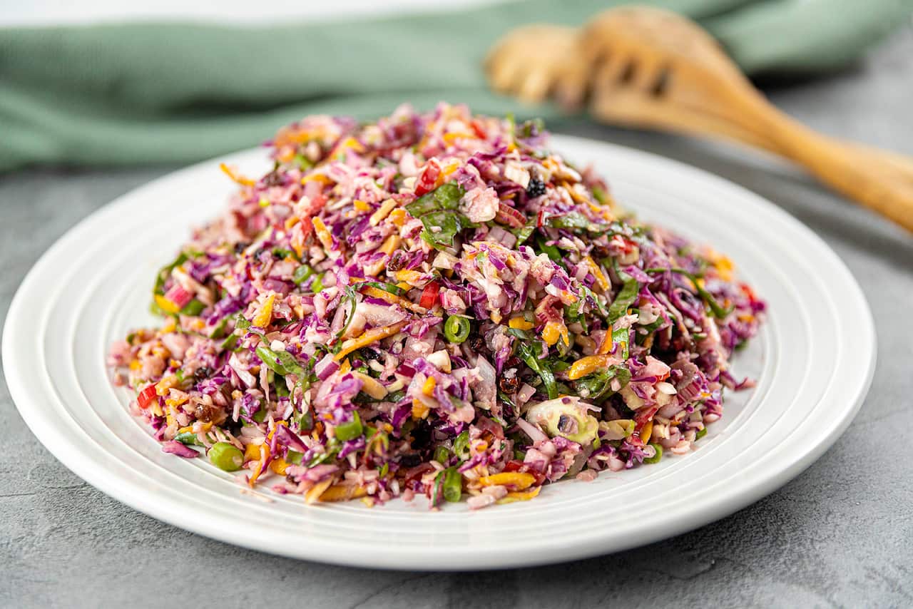 A wide white plate holds a mound of colourful red cabbage, chard and bean salad. 