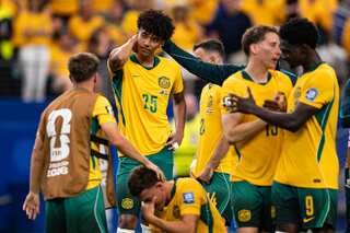 Socceroos players in green and gold console each other on the pitch moments after their loss to Egypt.