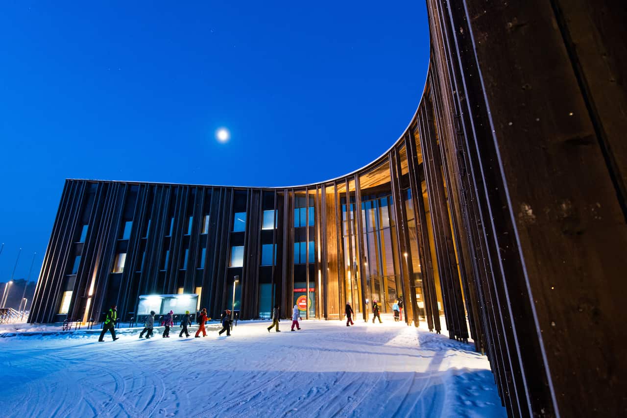 Snow on the ground outside a large building.