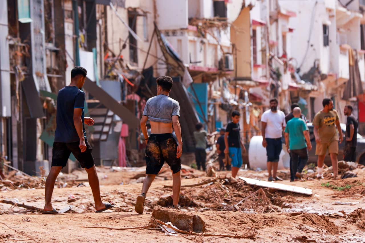 People walk through streets damaged by floods