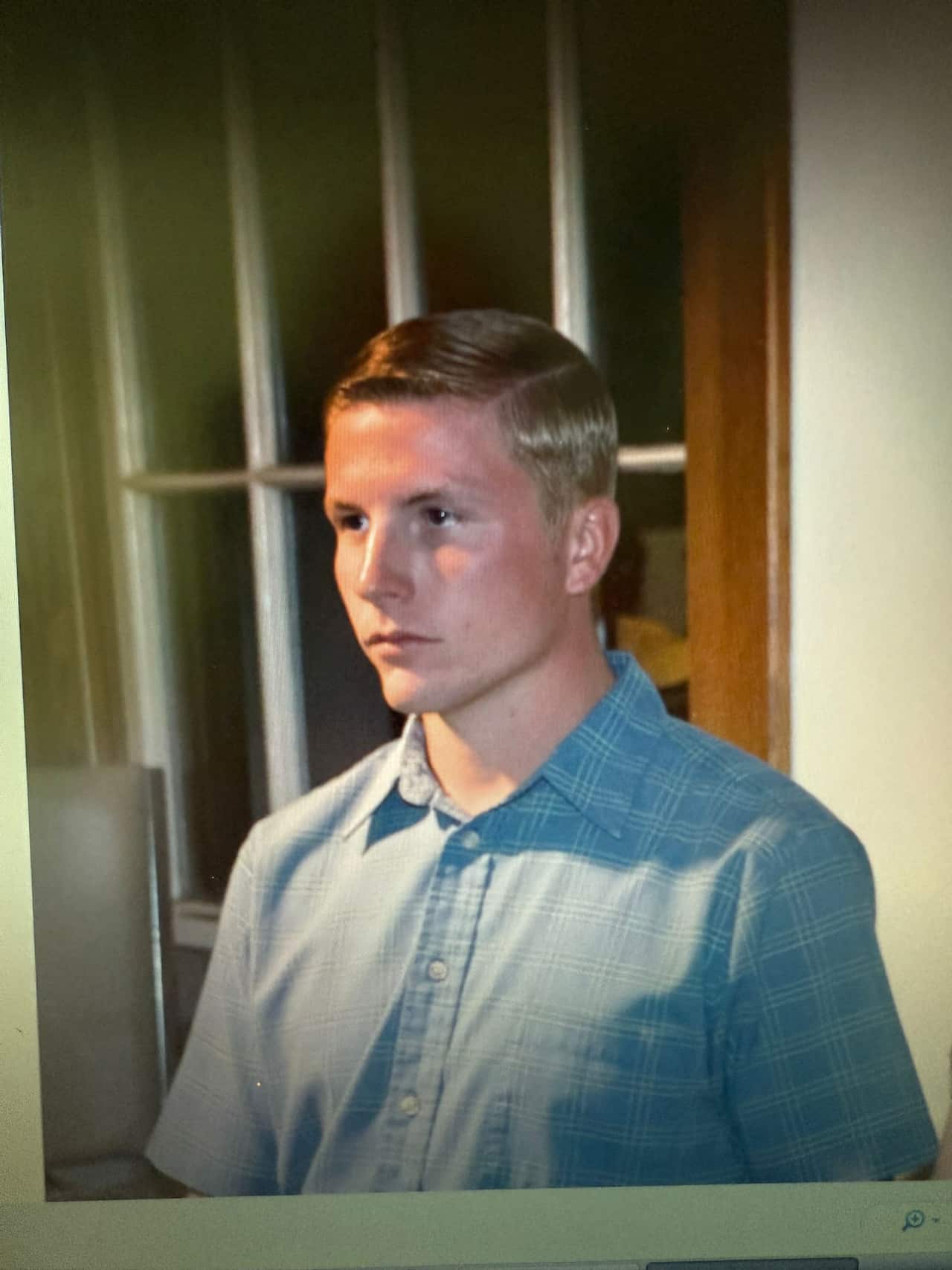 A picture of a young man with blonde hair. He is looking to his left and has a neutral facial expression. 