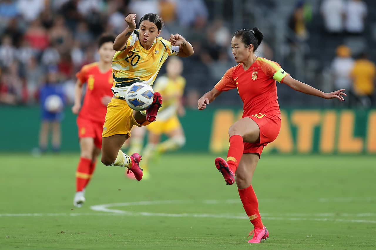 Woman wearing yellow uniform beats woman wearing red to the ball during a soccer match