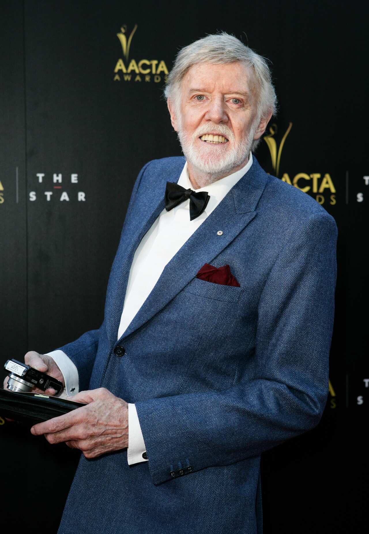 A man wearing a suit and bow tie who is smiling.