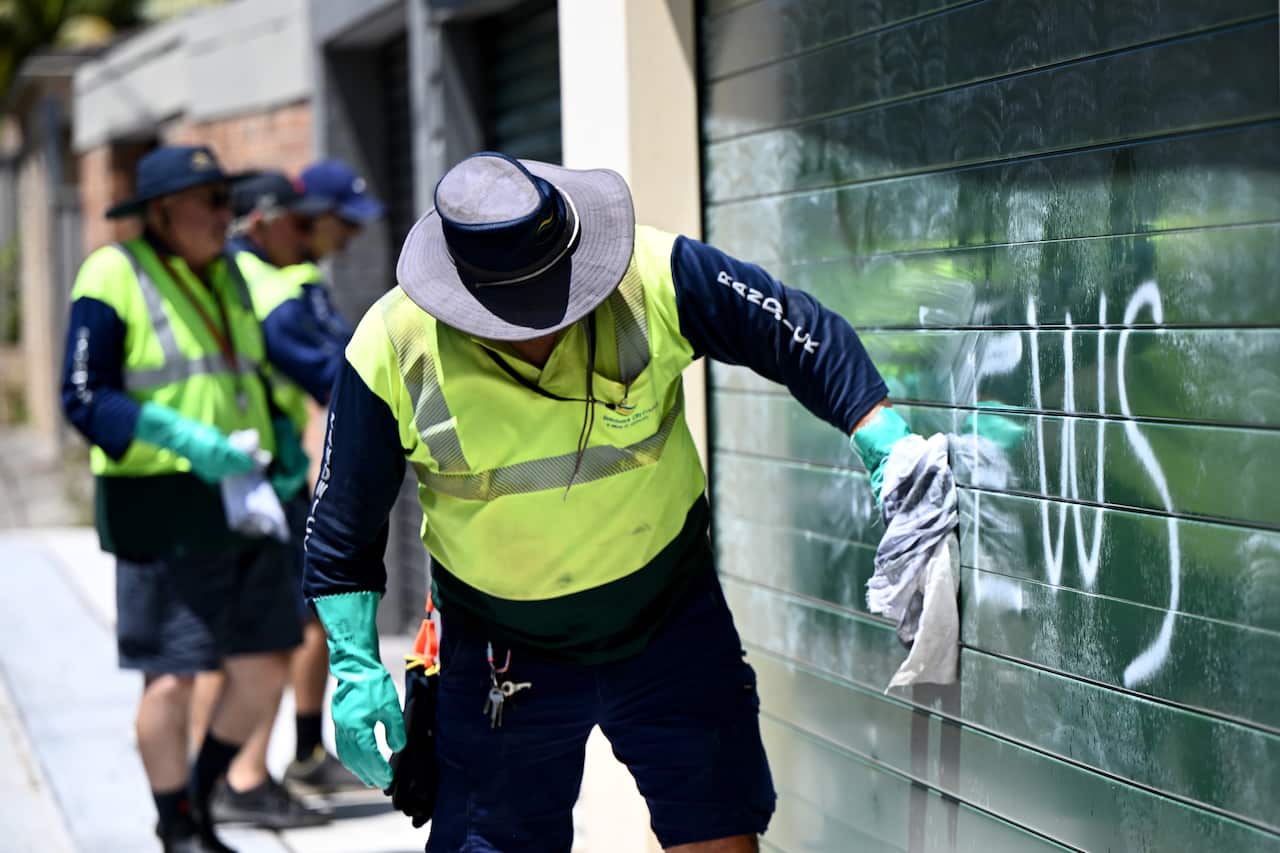 People cleaning a vandalised garage.