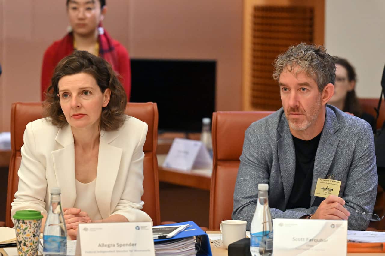 A woman in a white suit sitting next to a man in a grey suit 