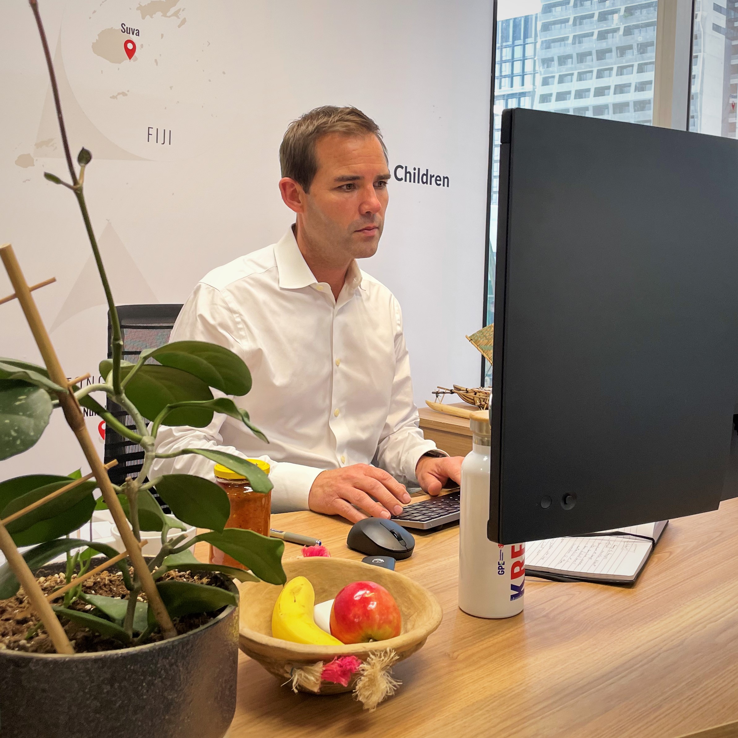 A middle-aged white man looks at a computer screen in an office environment.