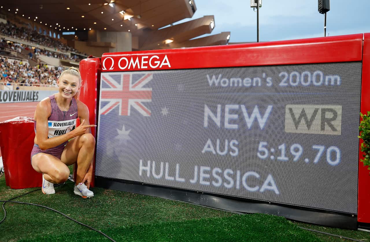 A woman poses next to an electronic sign