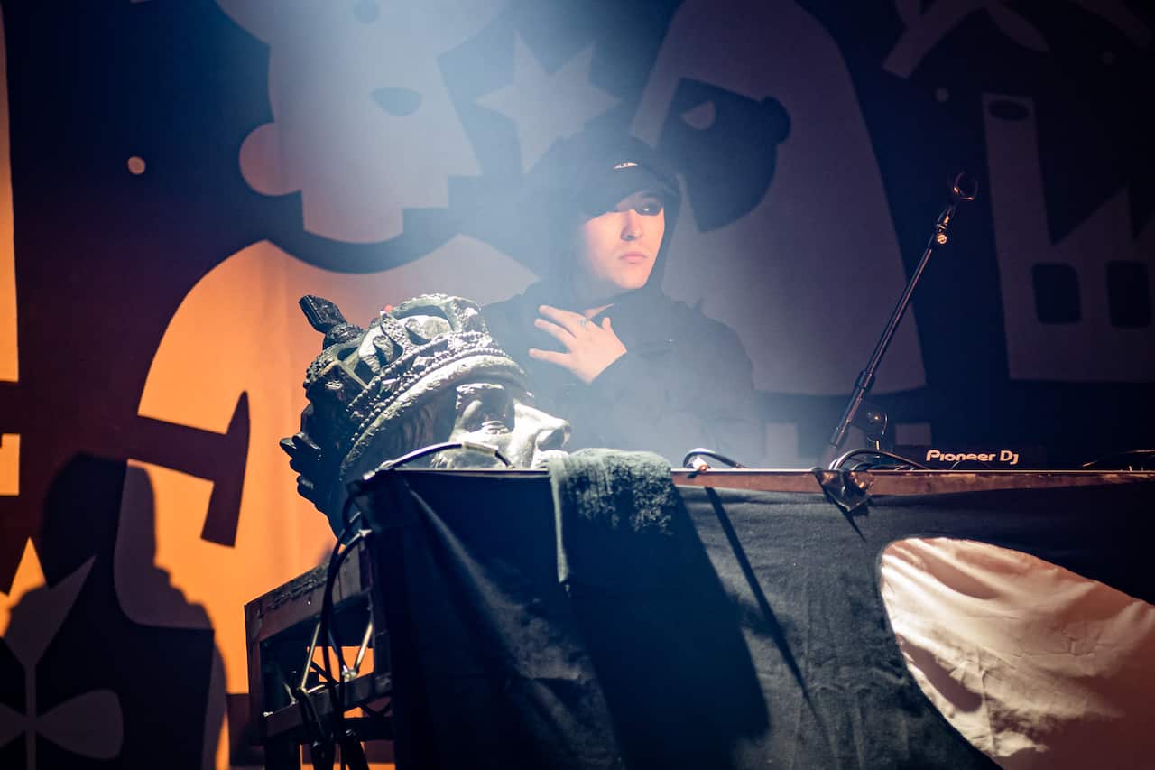 A man on stage with a cap on. 