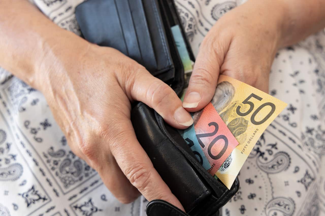 A person opening their wallet. Inside are Australian banknotes.