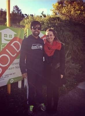 A man and a woman standing in front of a sold sign 