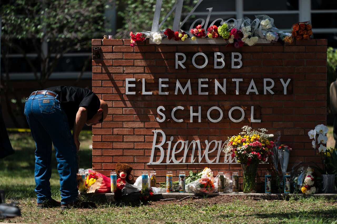 A law enforcement officer lights a candle outside Robb Elementary School in Uvalde, Texas