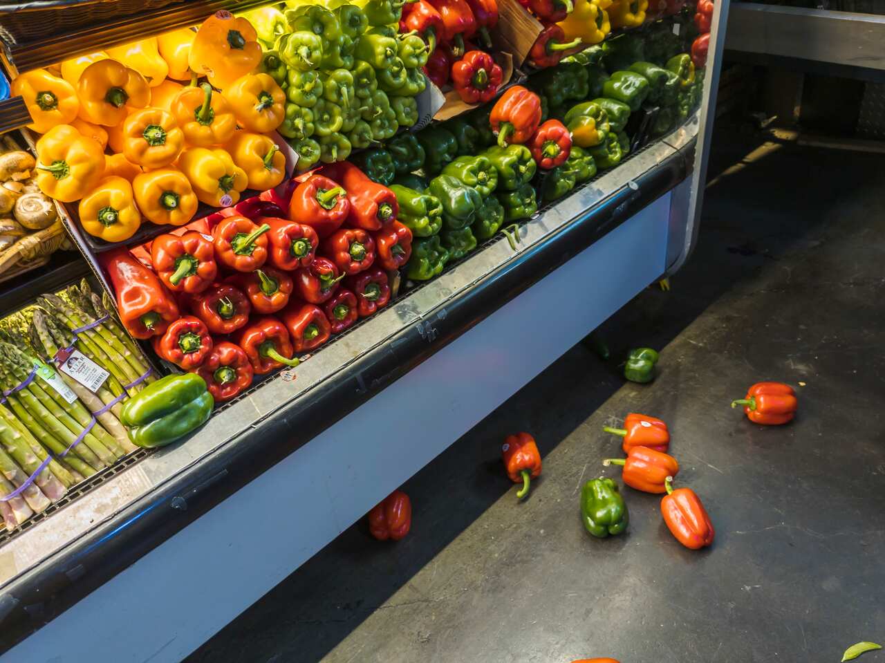Capsicums in a fridge with some spilled on the floor.