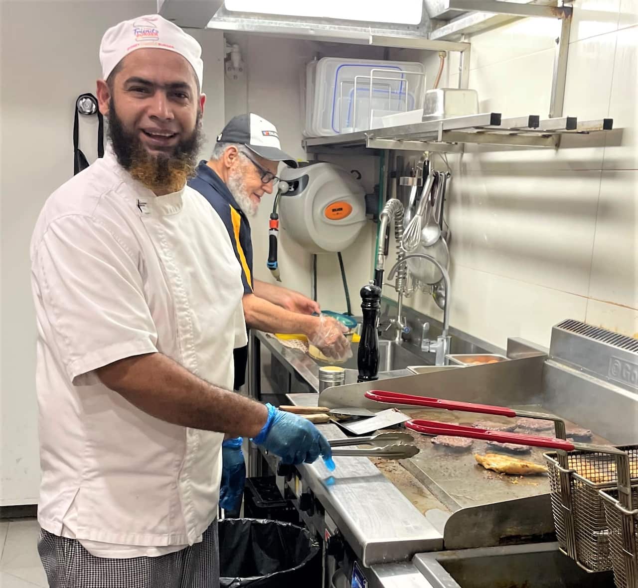 Masum Alam cooking burgers in his shop