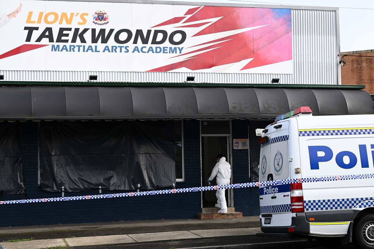 An exterior view of a taekwondo studio with a police van outside it