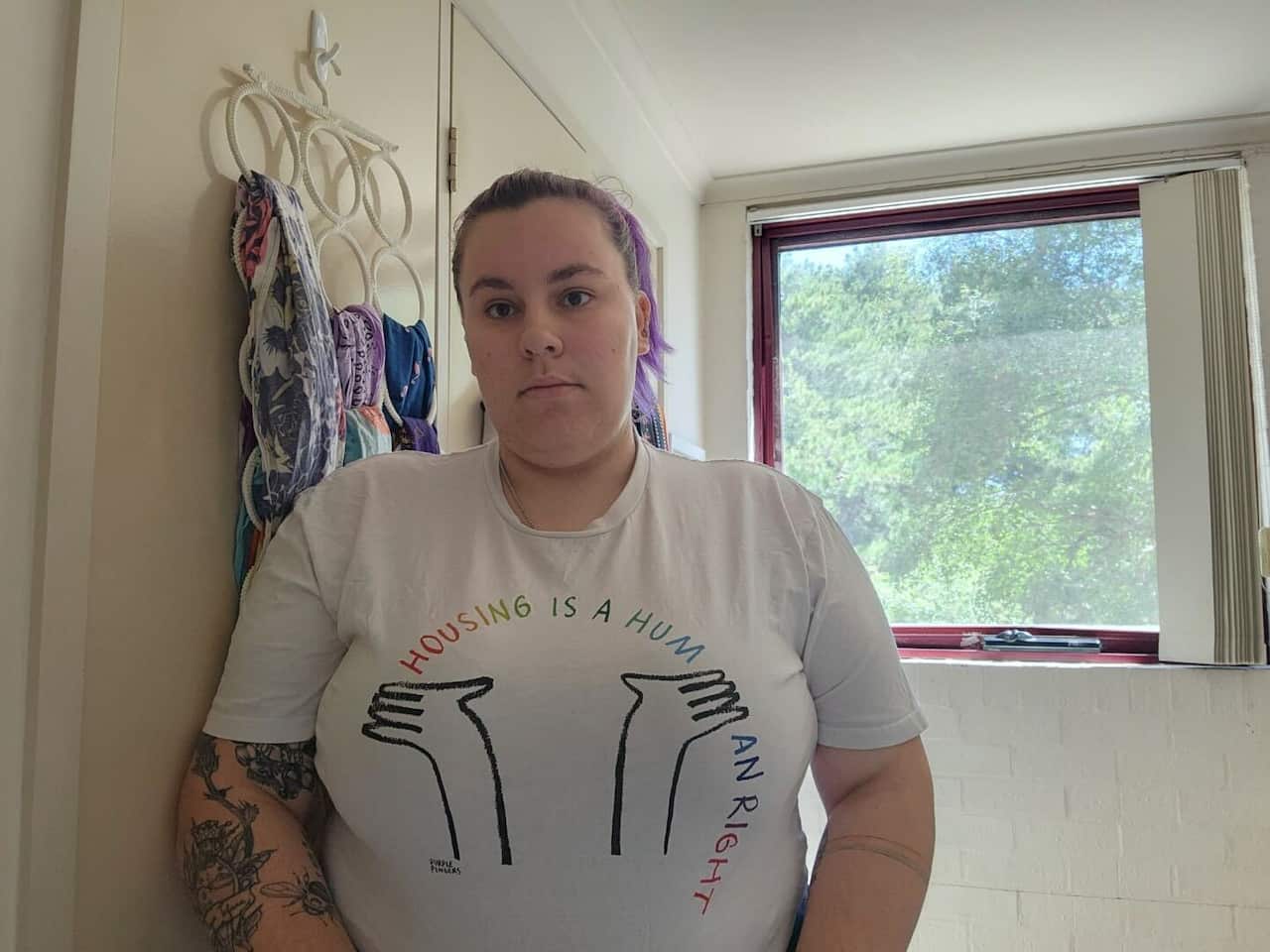 A woman wearing a t-shirt looks at the camera