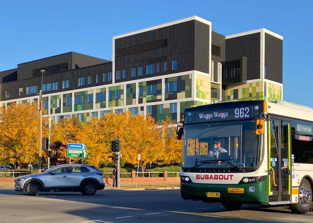 A bus and a car on a road in front of a large building
