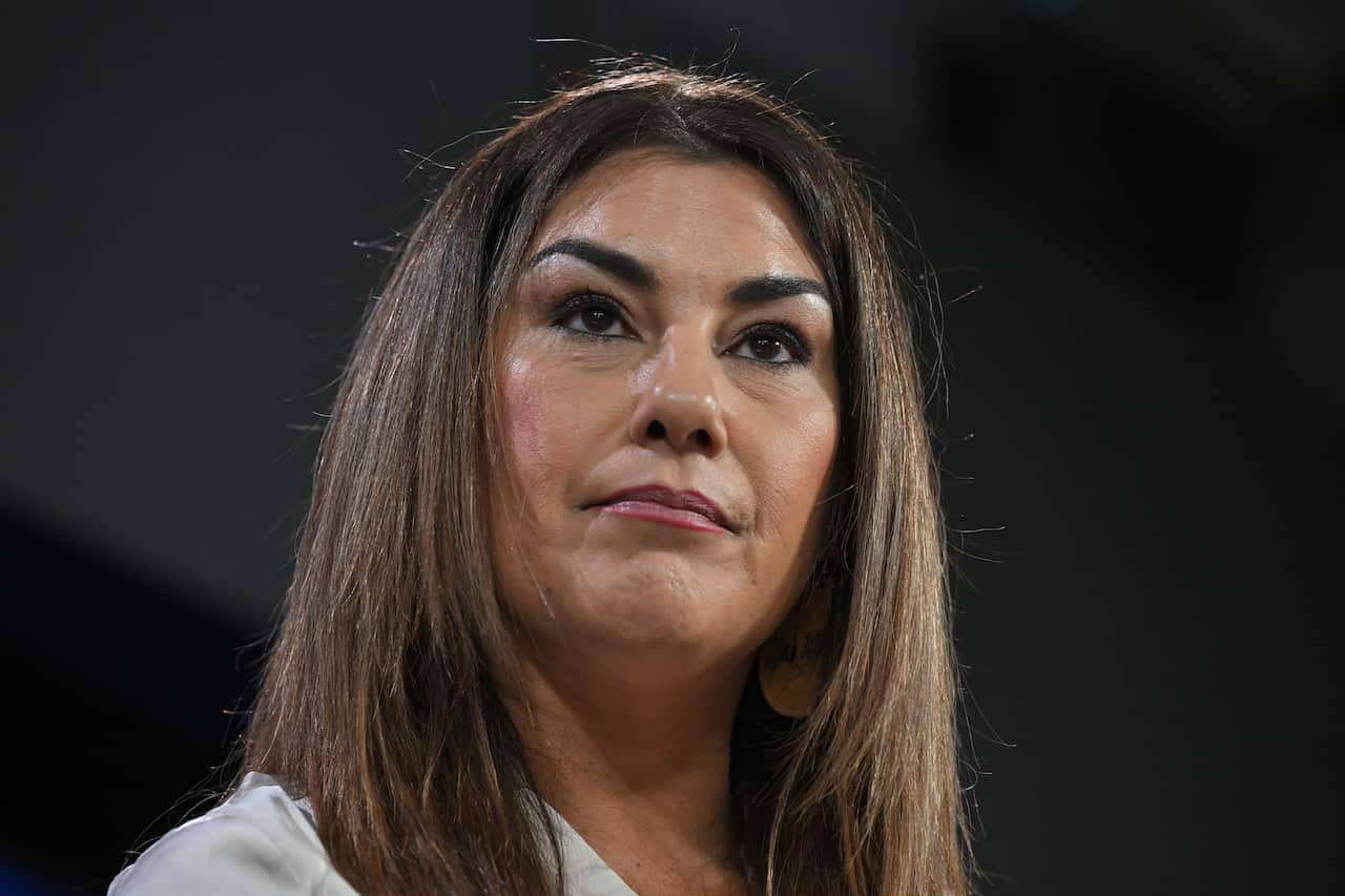 Lidia Thorpe, wearing a white shirt, looks out seriously from the camera.