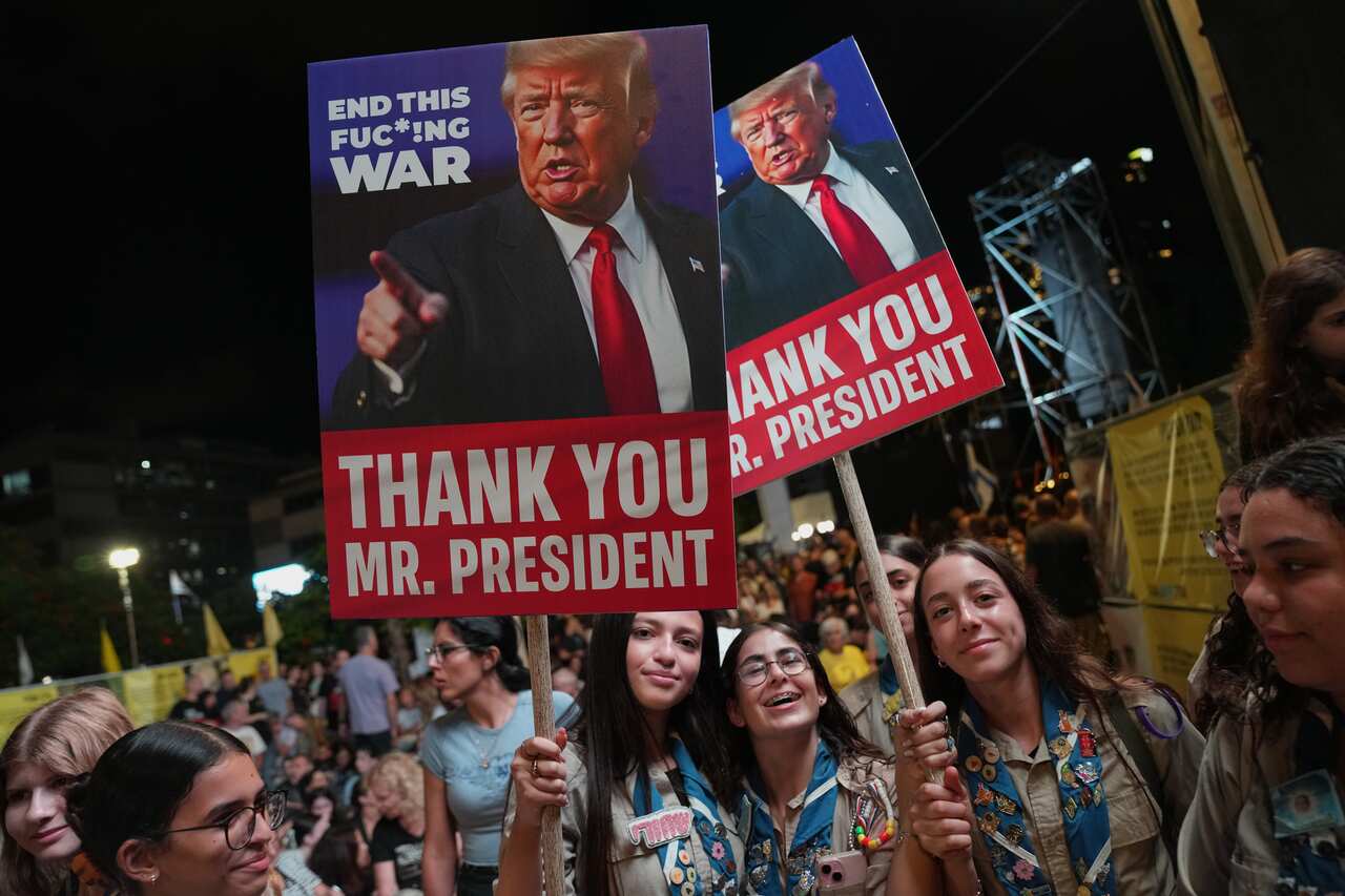 People hold up signs with images depicting the US President Donald Trump at a rally