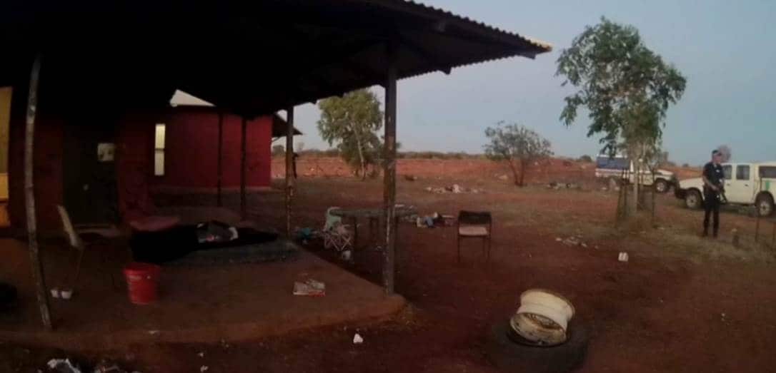 A police officer holds an AR15 assault rifle standing outside a house in the remote community of yuendumu