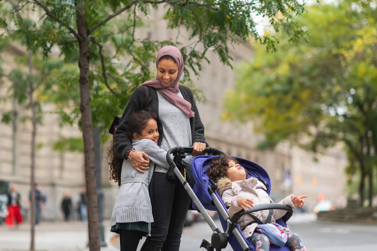 Muslim woman walking with daughters in city