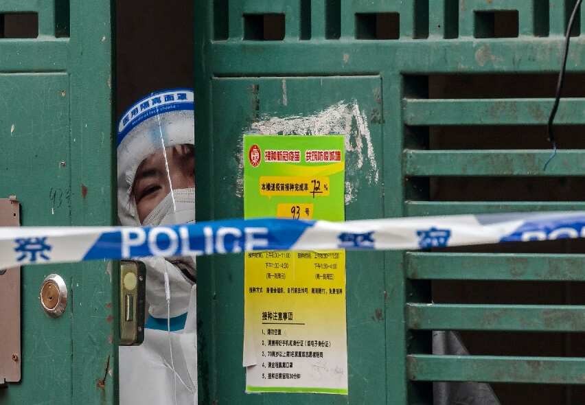 A health worker peers through a door in a building that has been cordoned off by authorities. 