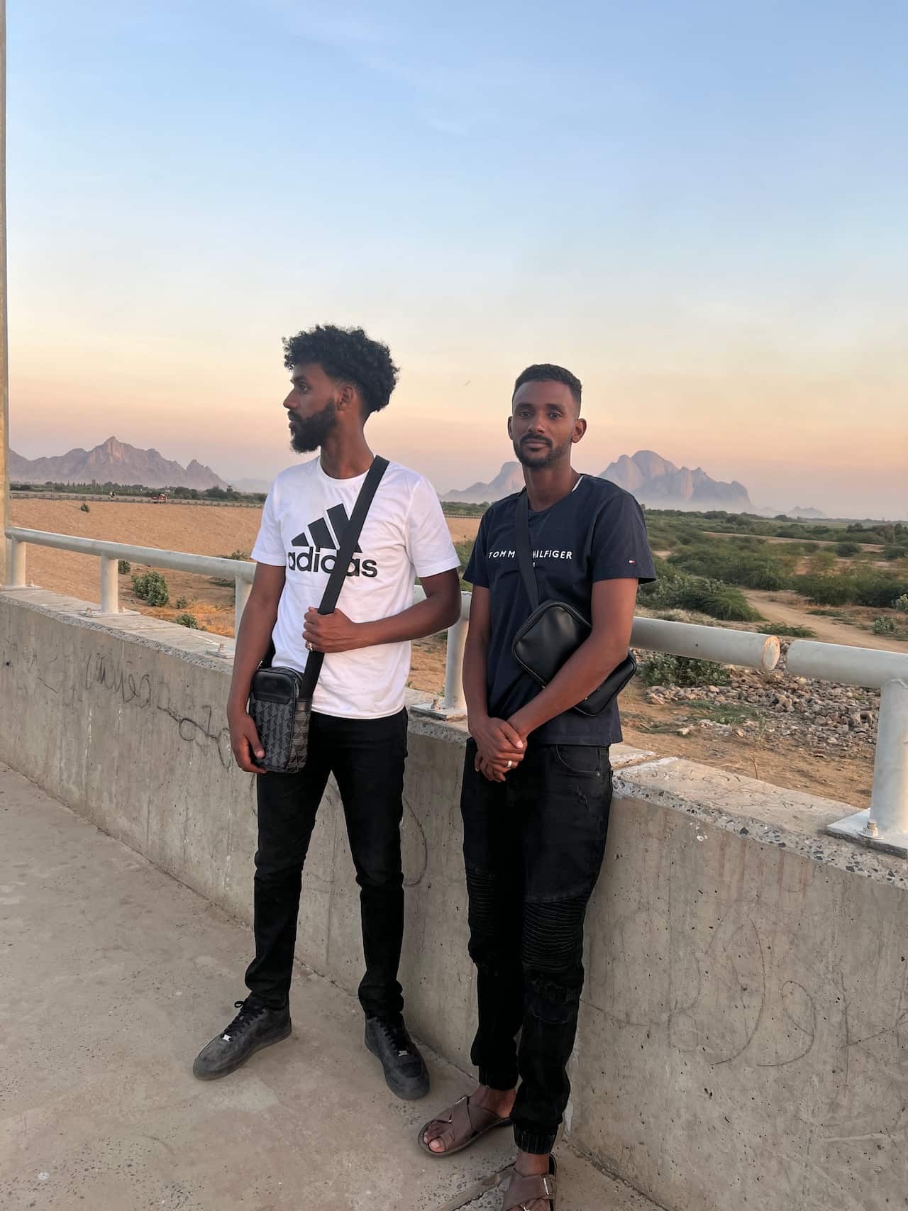 Two Sudanese Australian men stand together and look at the camera.