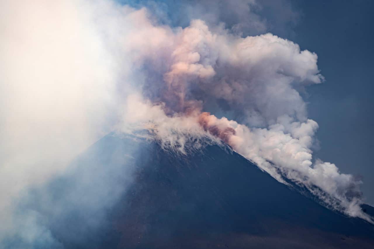Smoke clouds billowing from the top of a volcano.