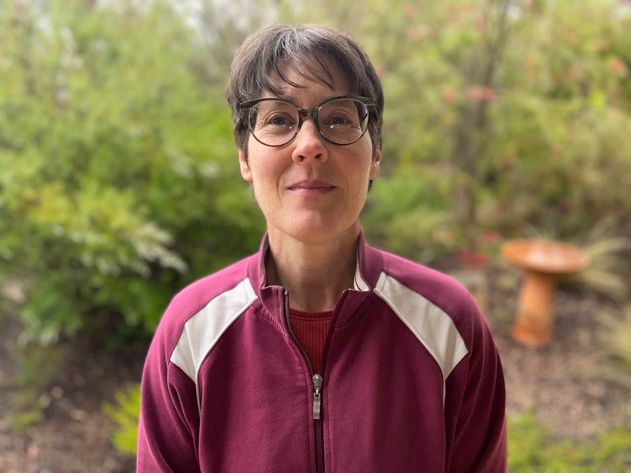 Woman wearing glasses standing in bushland.