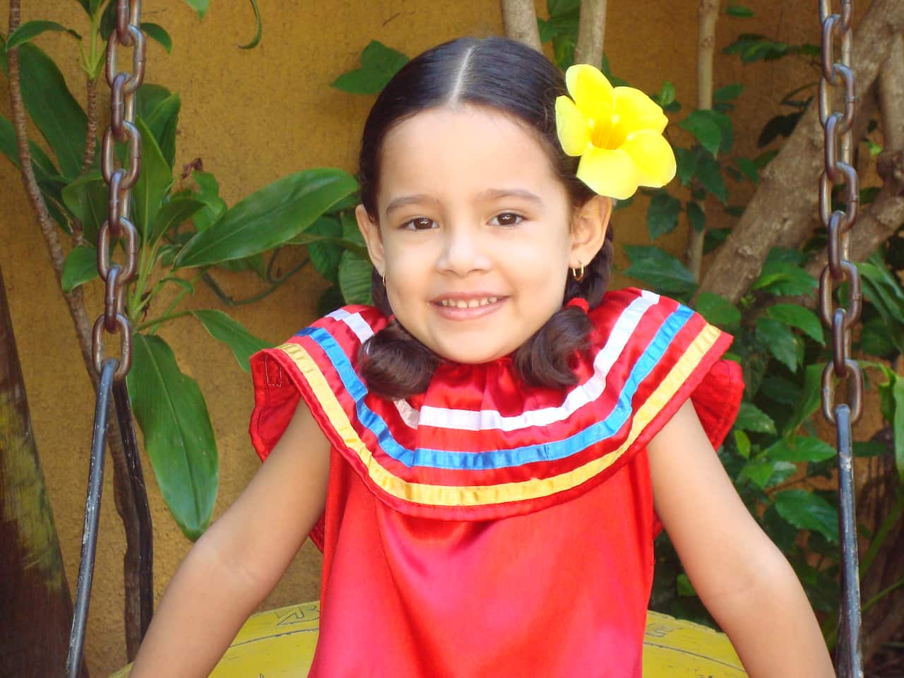 Sofia as a young child wearing a brightly coloured dress in Bolivia.