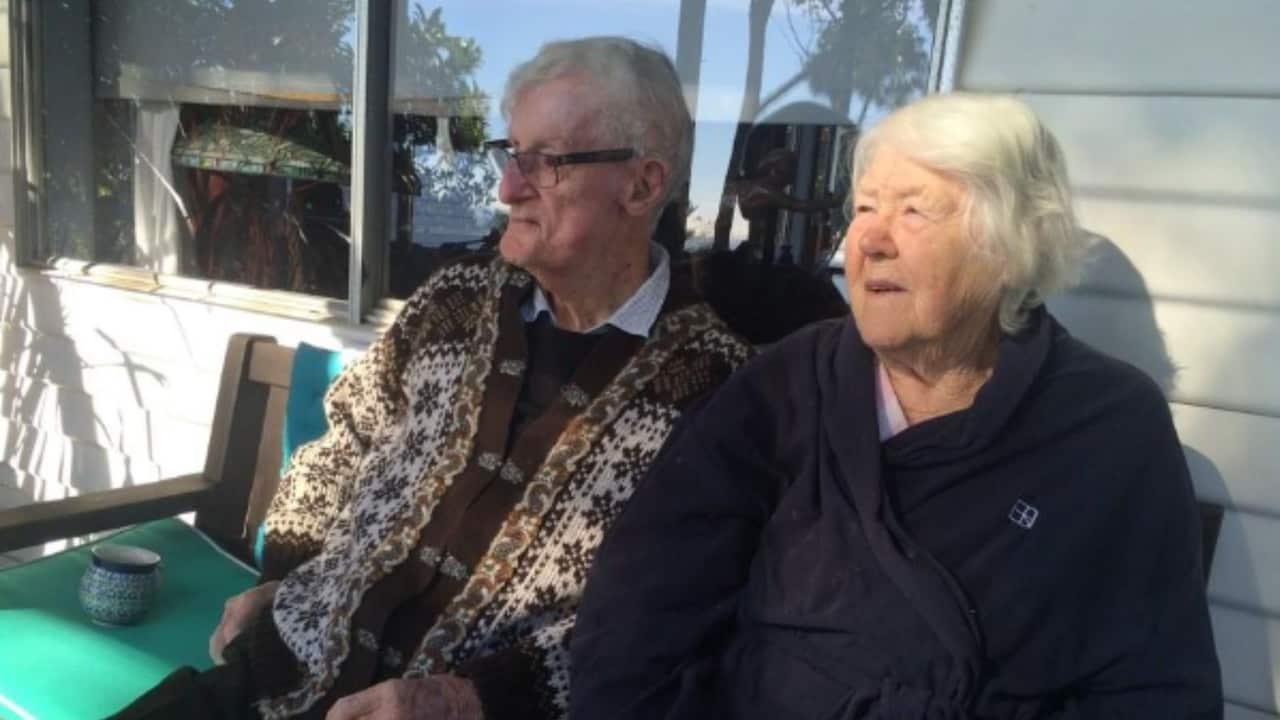 an older man and woman in warm clothes sitting outside
