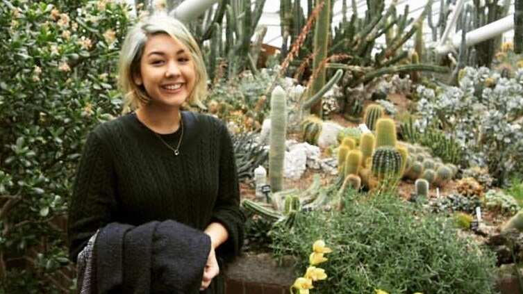 Woman standing in a garden smiling at camera.
