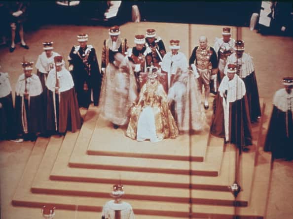 Queen Elizabeth II sitting on the throne and wearing a crown during her coronation in 1953.