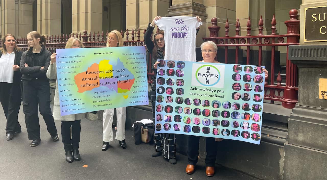 Women standing outside court holding placards.