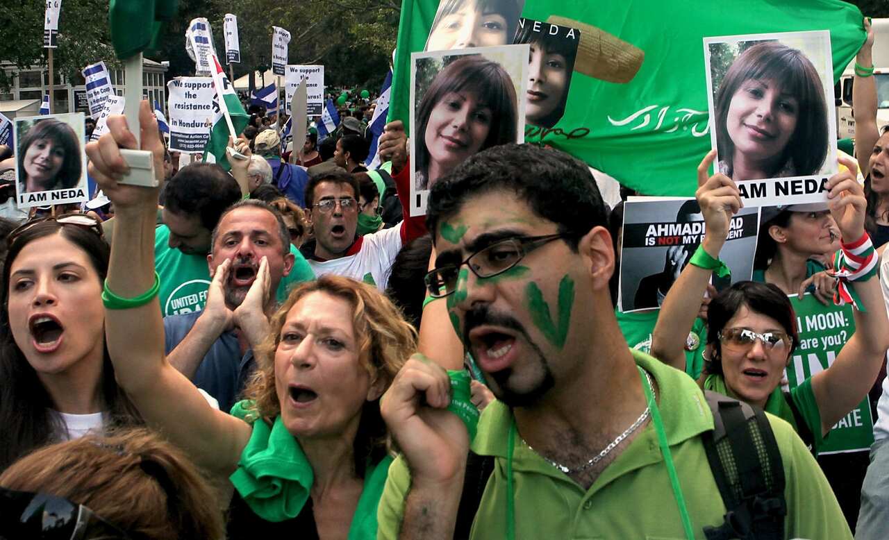 People wearing green gather in protest while carrying a picture of a girl 