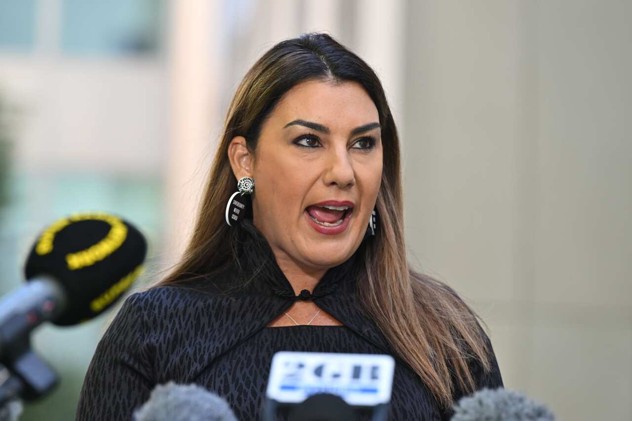 A woman speaking in front of microphones.