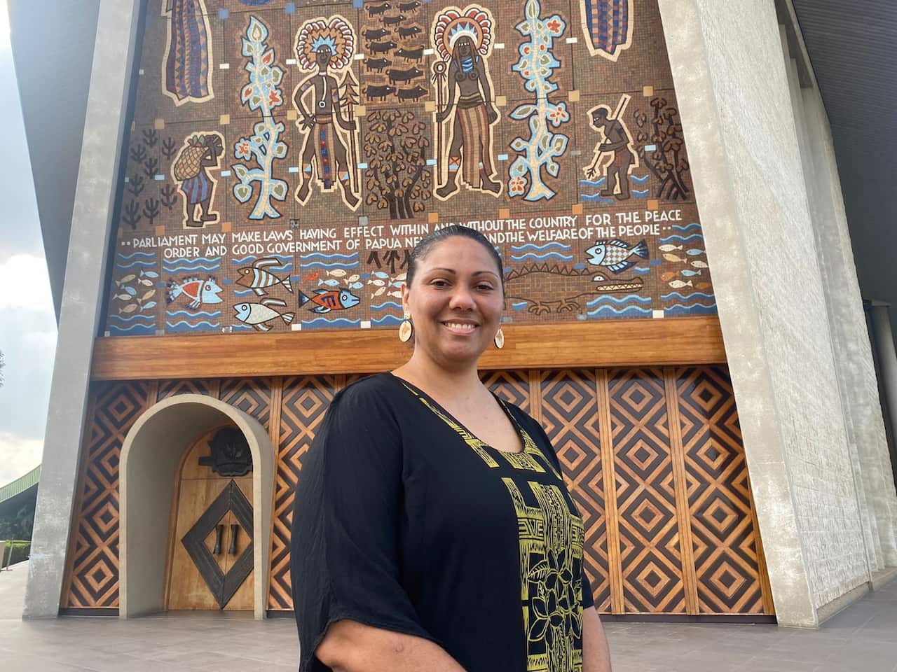Sylvia Pascoe stands in front of the Papua New Guinea parliament building 
