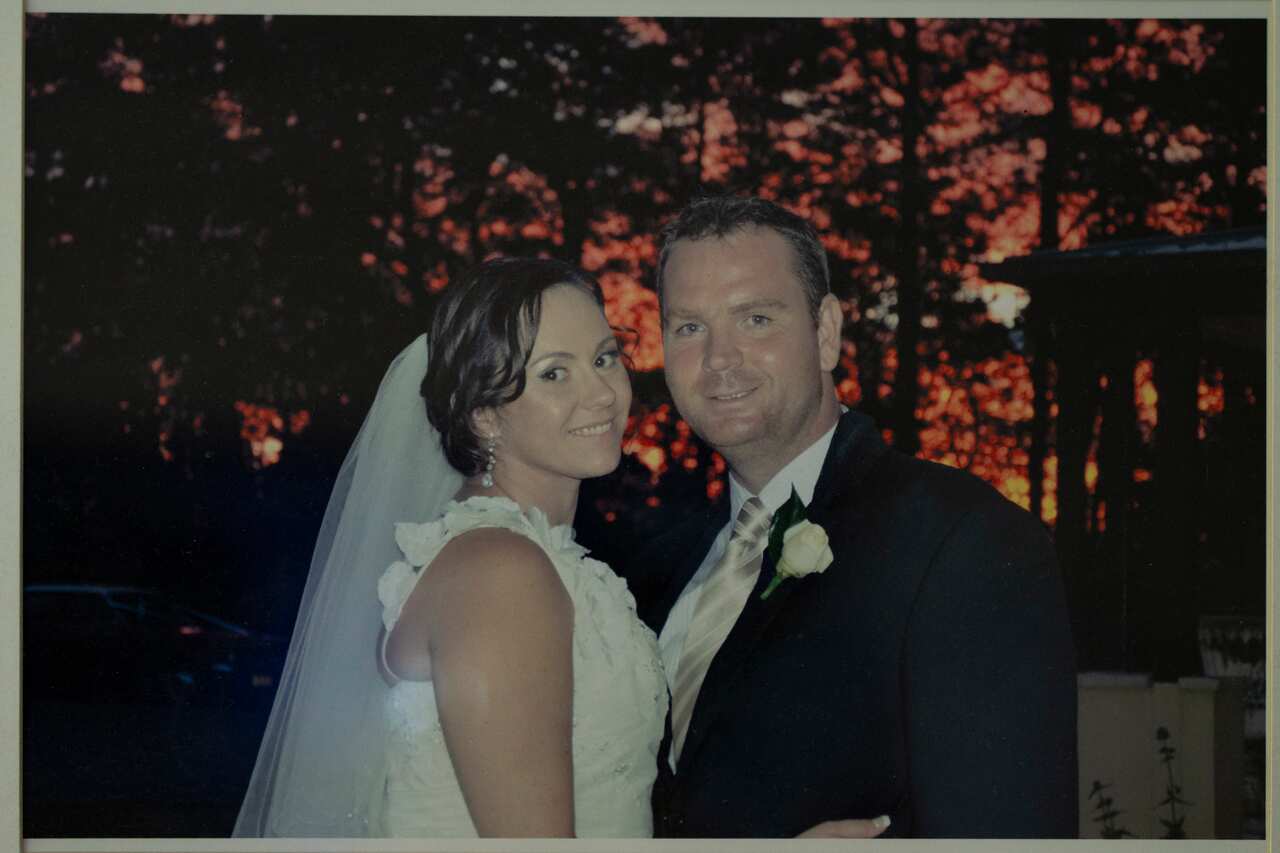 An old photo of a couple on their wedding day, with the bride wearing a white gown and veil on the left, and the groom in a black suit with a cream tie.
