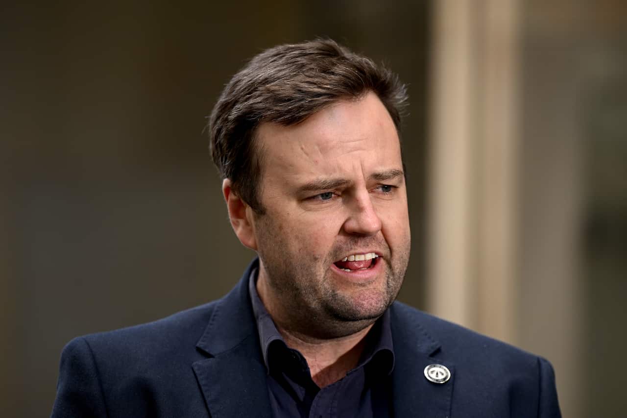 A man in a dark blue suit is speaking.