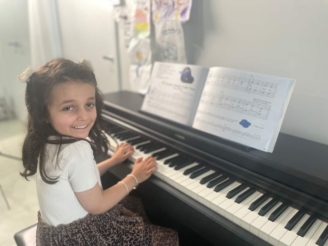 A girl sits in front of a piano.
